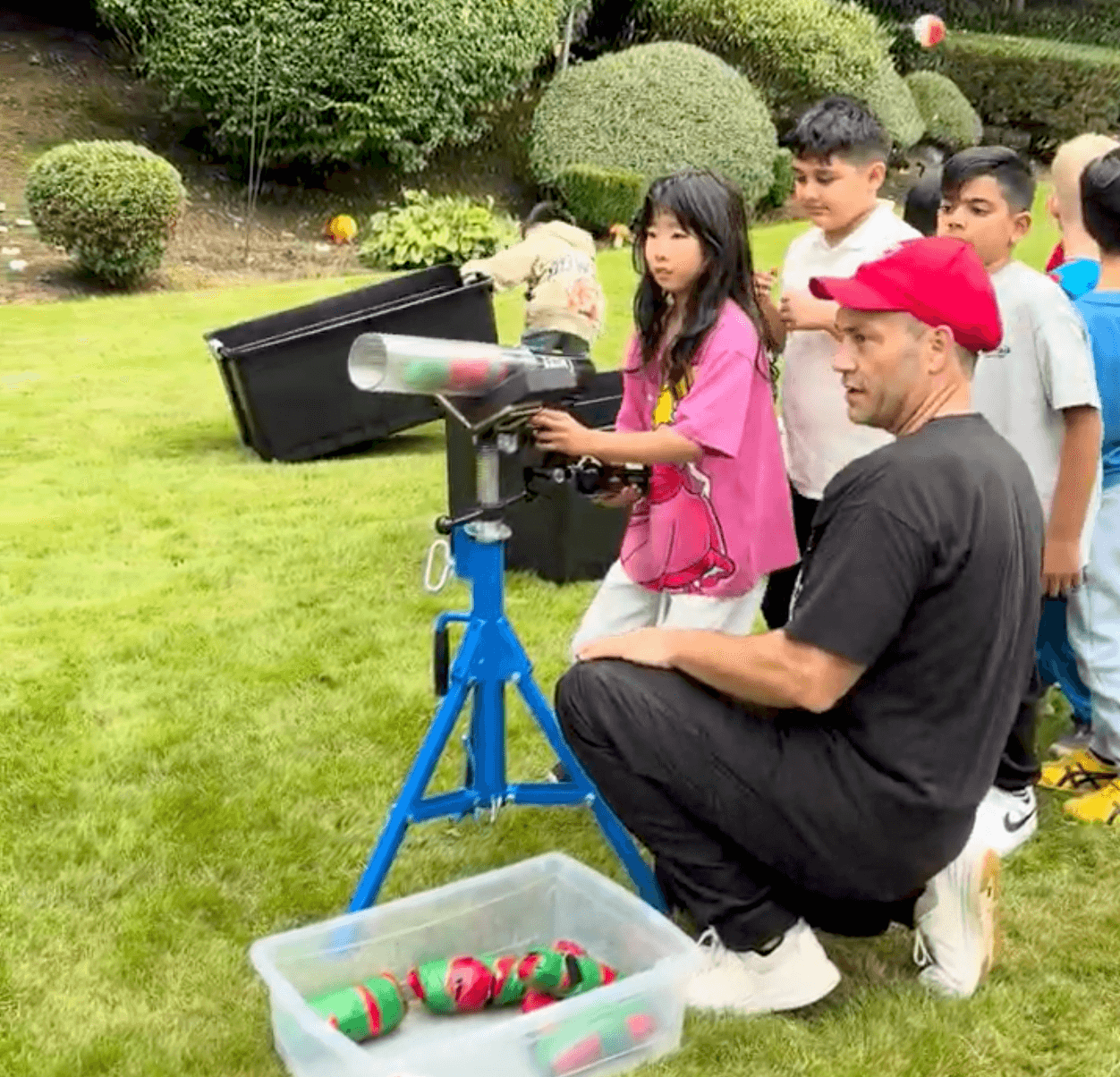 A girl firing the t-shirt cannon on the lawn at a Vancouver kids birthday party while the other kids line up for their turn.