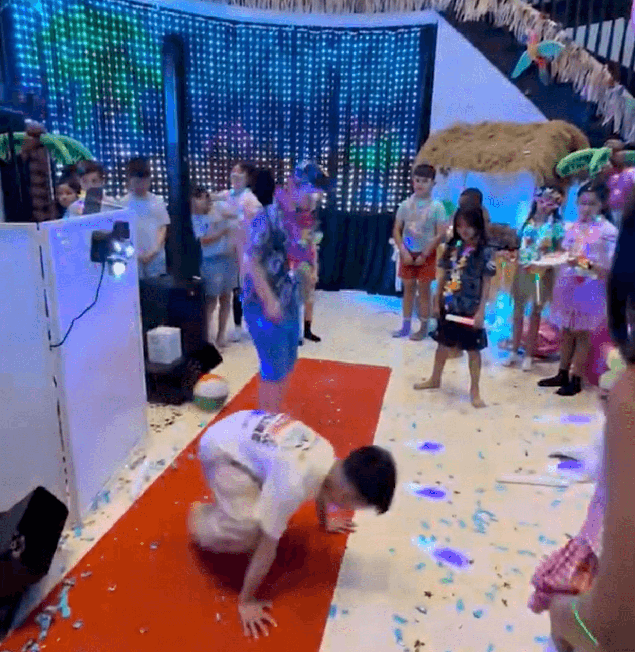 A child breakdancing on the red carpet while the other kids watch from the circle at a Vancouver birthday party.