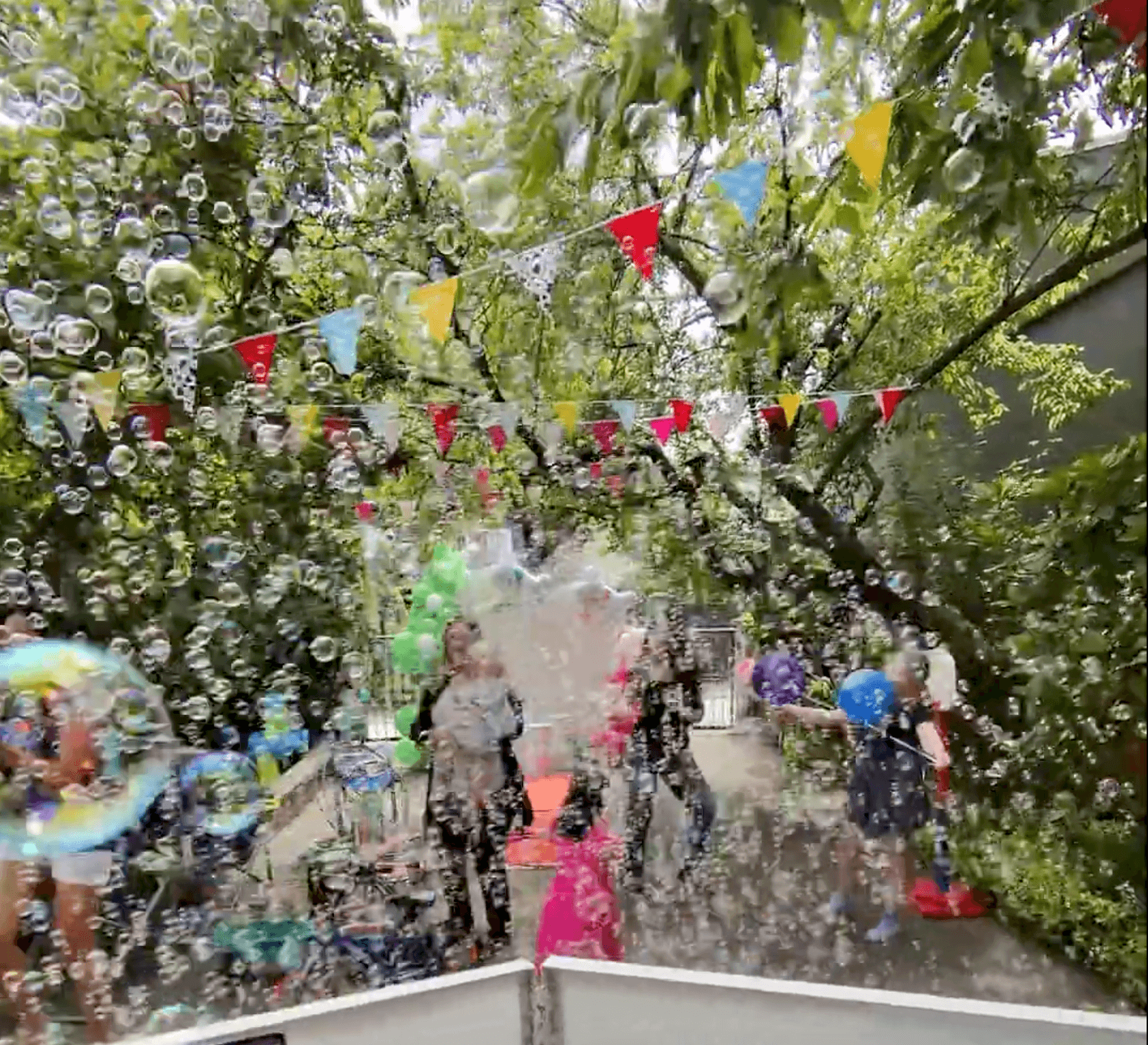 A backyard filled with bubbles and bunting as the kids run through them at the finale of a Vancouver party.
