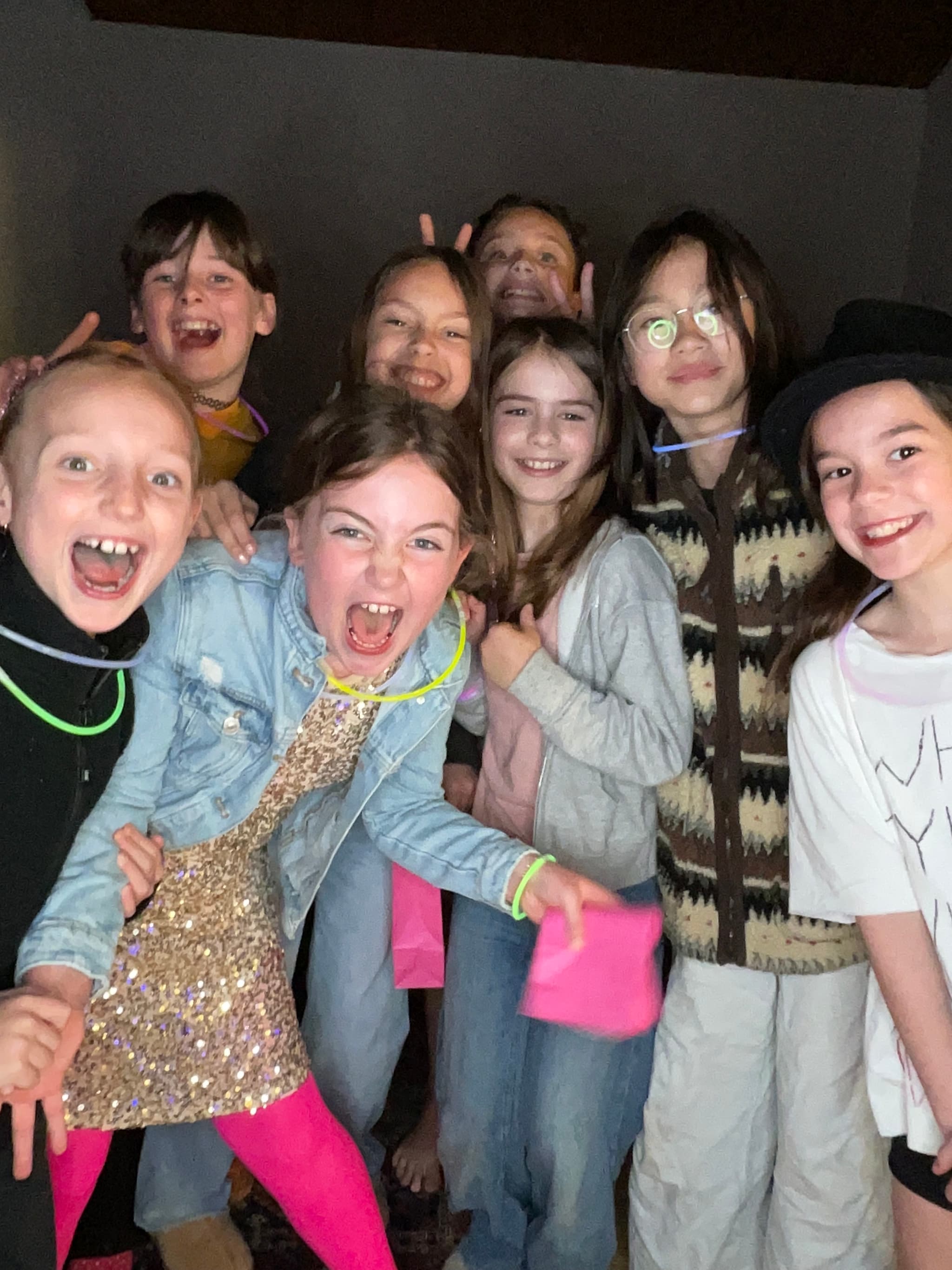 A group of girls in glow bracelets laughing together at a Vancouver birthday party.