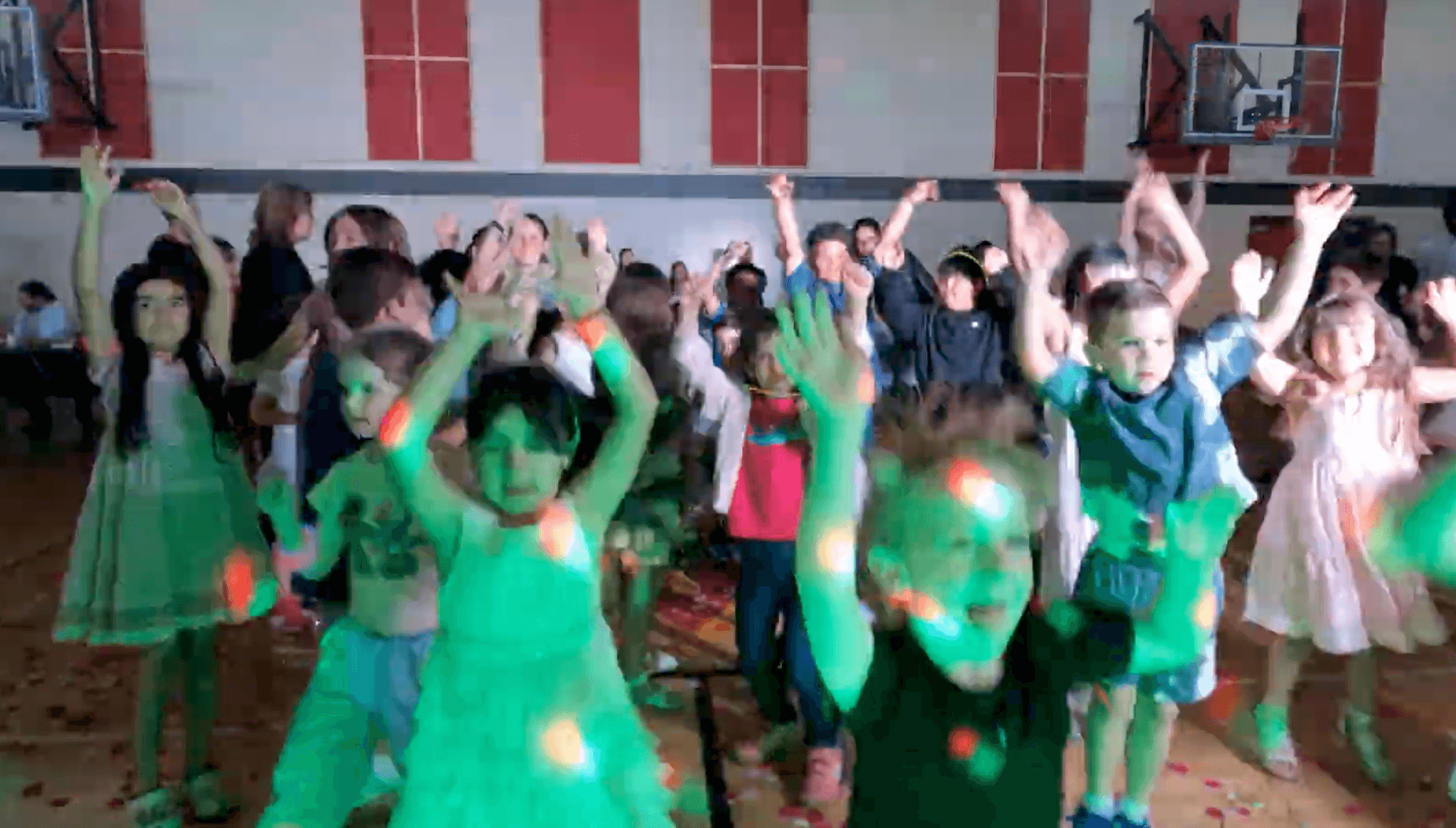 A gym full of kids with their arms in the air during a group game at a Vancouver school event.