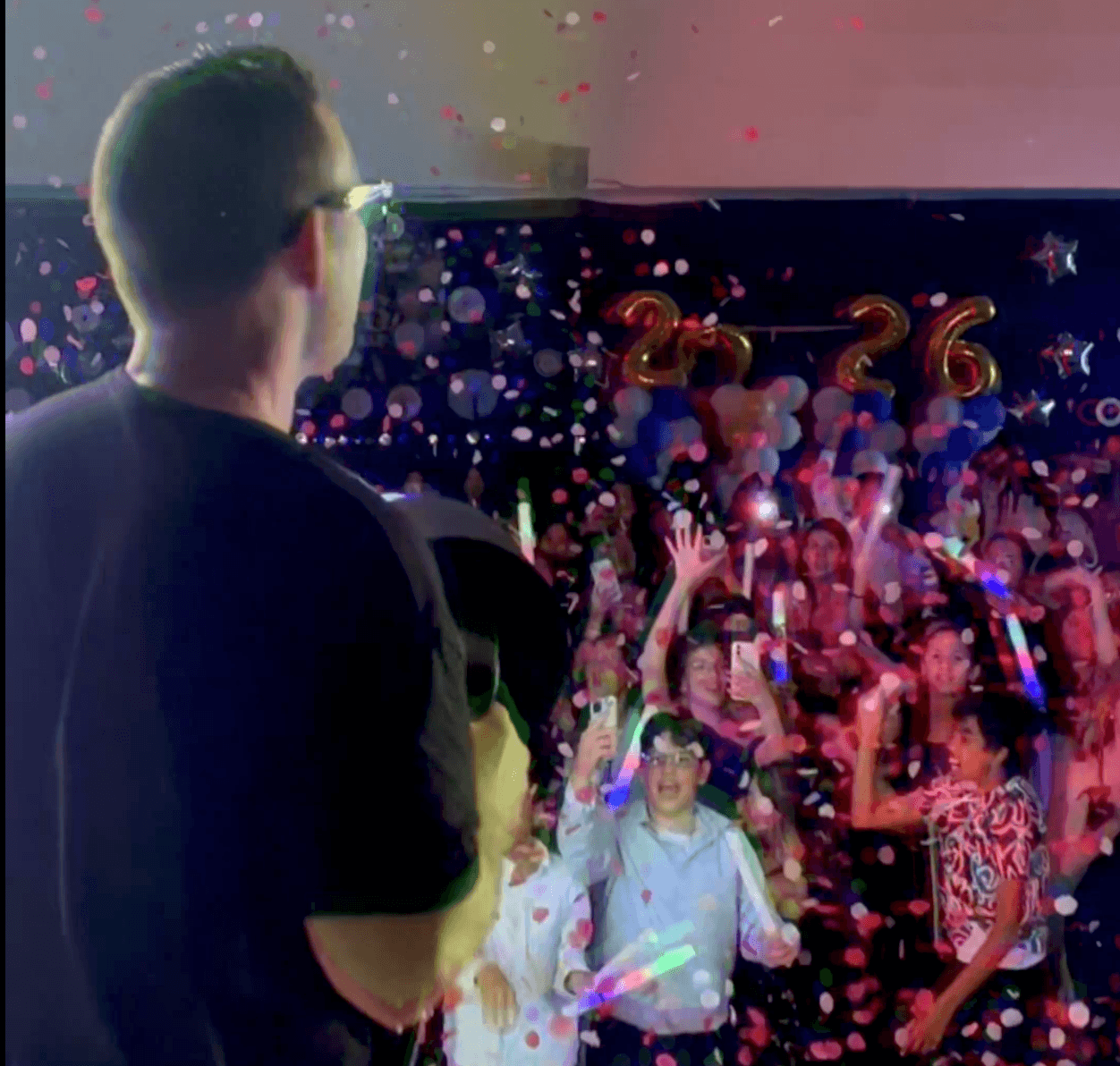 Students packed onto the dance floor under confetti and glow sticks at a Vancouver school event.