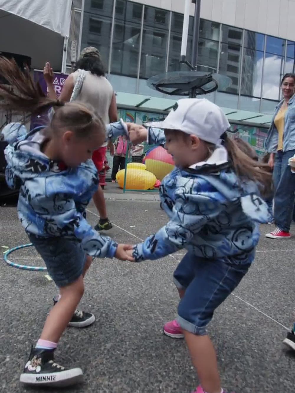 Two small children dancing together at an outdoor daytime baby rave in Vancouver.