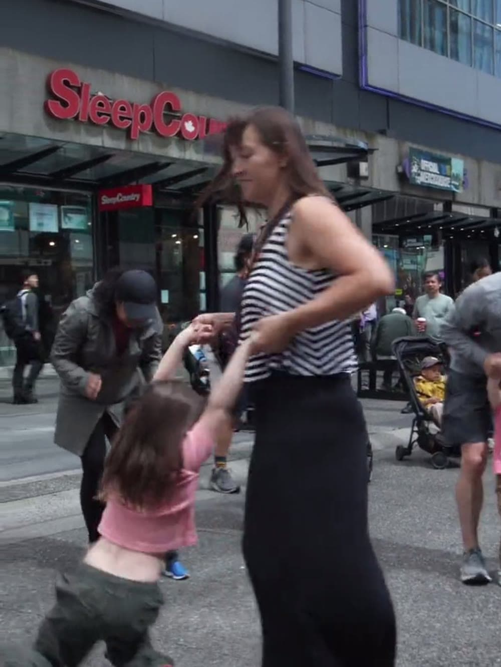 Parent dancing with a toddler in the street at a Vancouver baby rave.