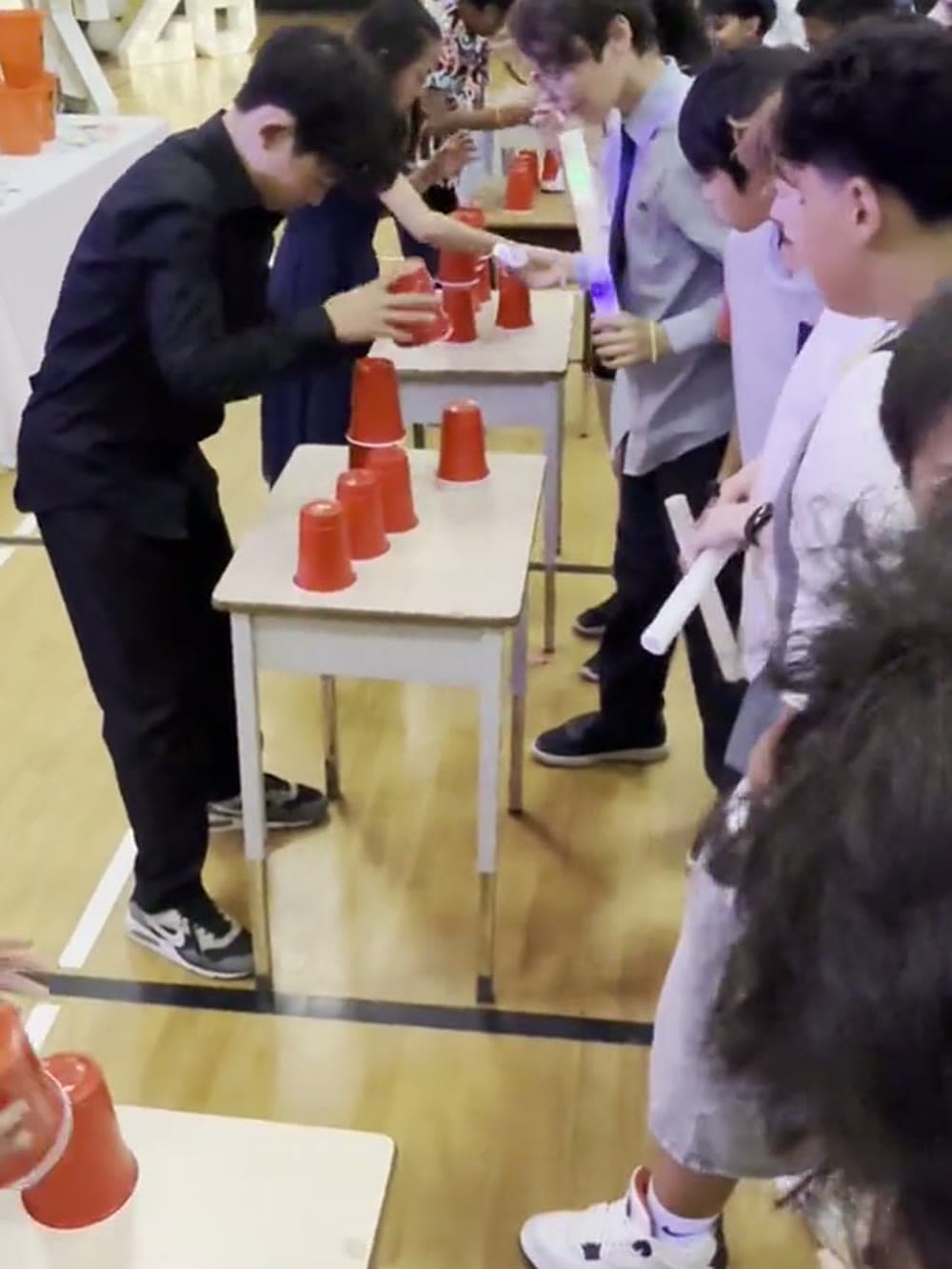 Kids racing a red cup game at a table while the rest of the group watches.