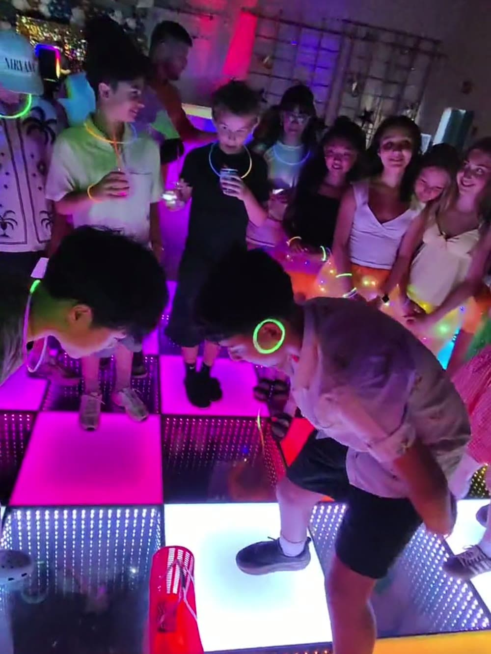 Kids dancing on a lit LED floor at a glow party in Vancouver.