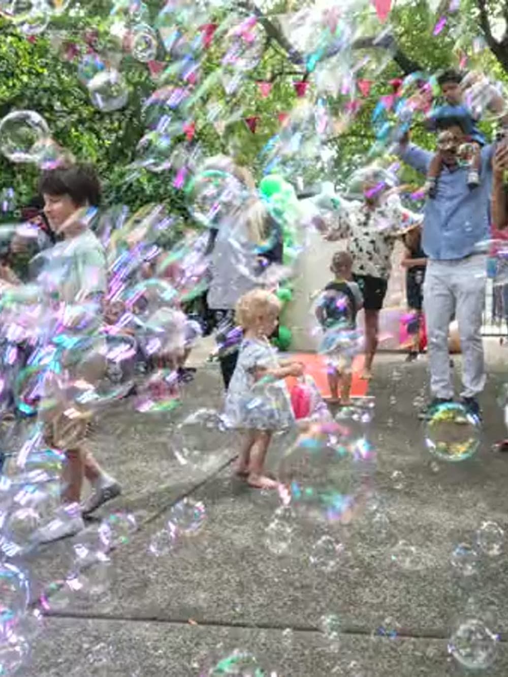 Children chasing bubbles from a bubble machine at an outdoor party in Vancouver.