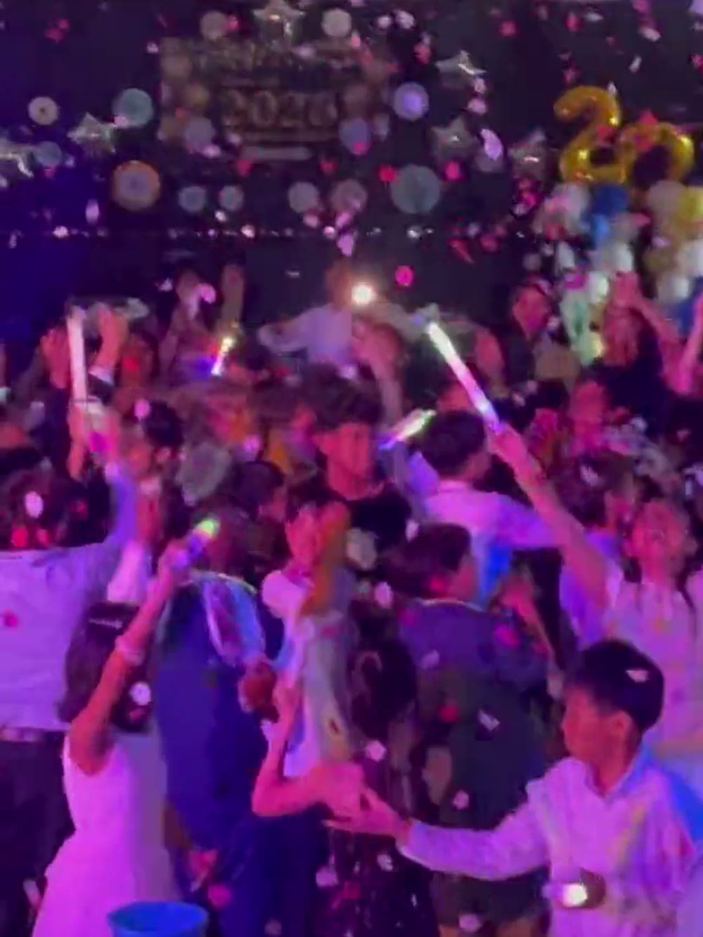 Packed dance floor under confetti and glow sticks at a Vancouver school dance.