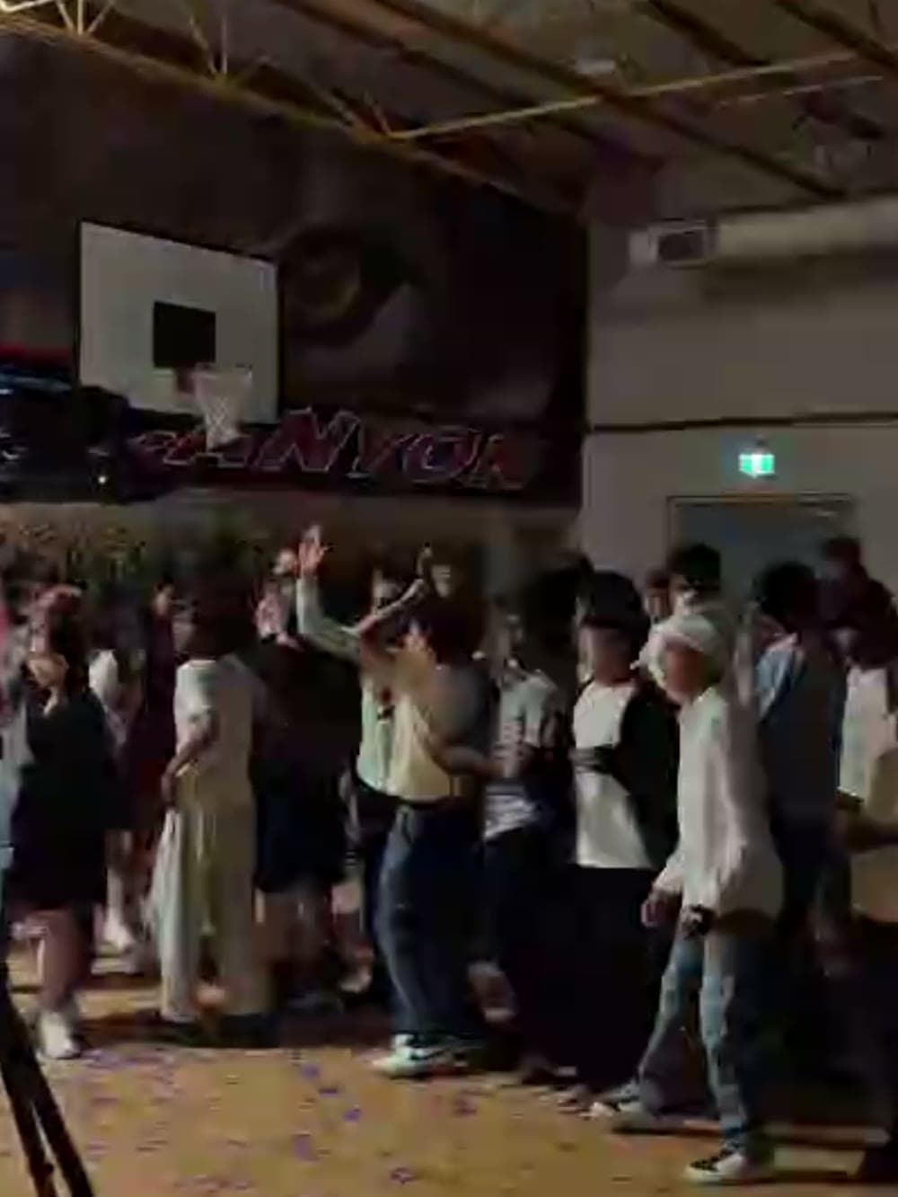 Students spread across a school gym floor dancing under confetti.
