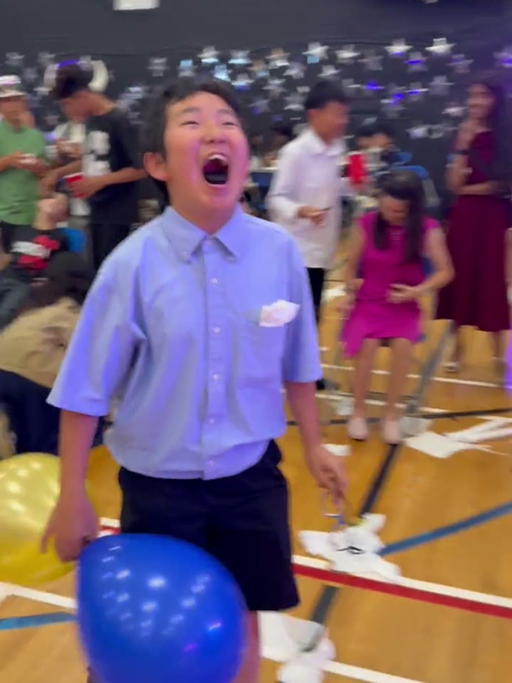 Student celebrating after winning a balloon game at a school event.